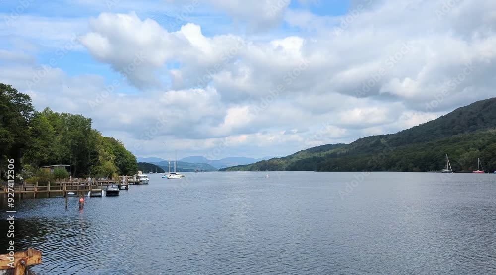Lake Windermere, Cumbria, still 4K stock video showing blue water, a blue cloudy sky, green forrest covered mountain, boats and jetty. Lake Windermere, Cumbria, still 4K stock video showing blue water, a blue cloudy sky, green forrest covered mountain, boats and jetty.
