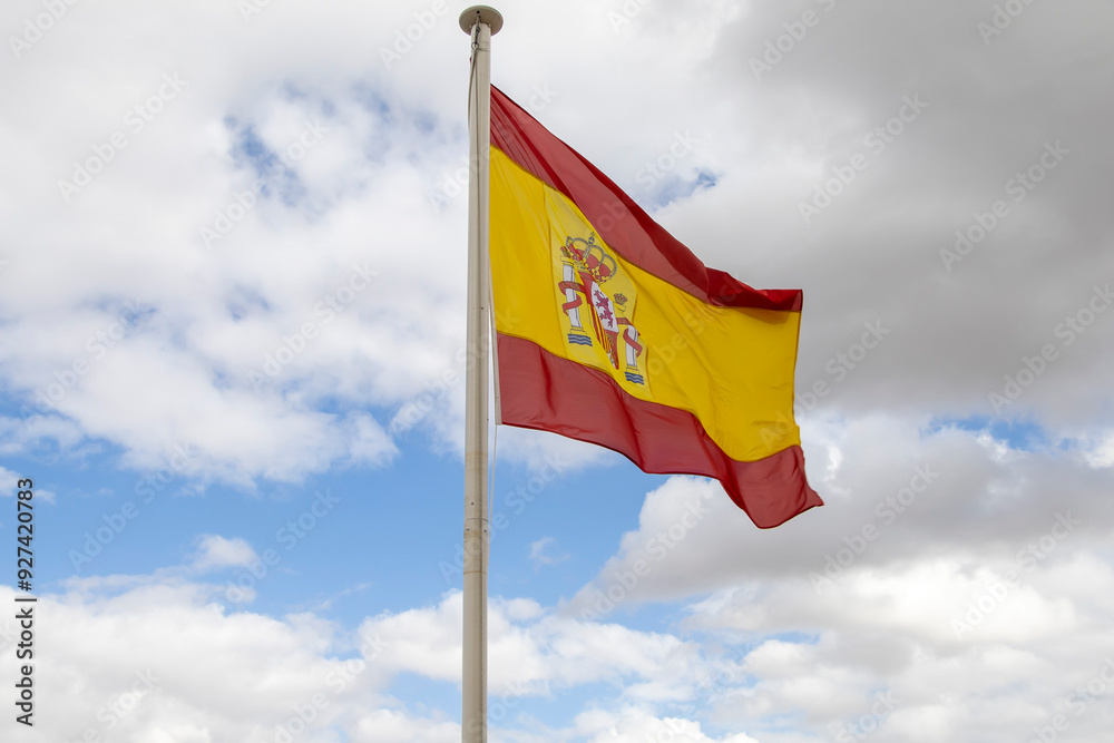 The bright sun illuminates the red and yellow stripes of the flag, creating a vibrant contrast against the backdrop of the blue sky and fluffy clouds. This image personifies the strength and beauty of The bright sun illuminates the red and yellow stripes of the flag, creating a vibrant contrast against the backdrop of the blue sky and fluffy clouds. This image personifies the strength and beauty of