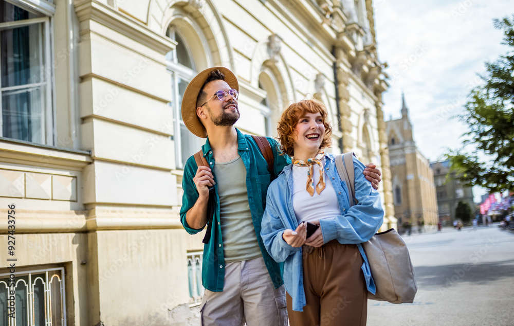 Young couple exploring the new city. Hugging and walking through the center. Wearing hats and backpacks. Young couple exploring the new city. Hugging and walking through the center. Wearing hats and backpacks.