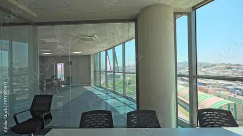 Spacious meeting room, office space with large windows during daytime without people. Blinds