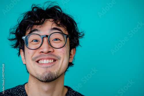 funny nerd Asina guy with quirky lens glasses. Smiling happy expression. Blue background. 