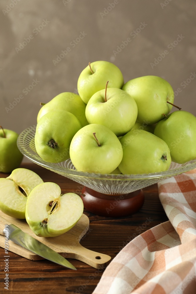 Glass vase with fresh green apples, cutting board and knife on wooden table against gray background, closeup Glass vase with fresh green apples, cutting board and knife on wooden table against gray background, closeup
