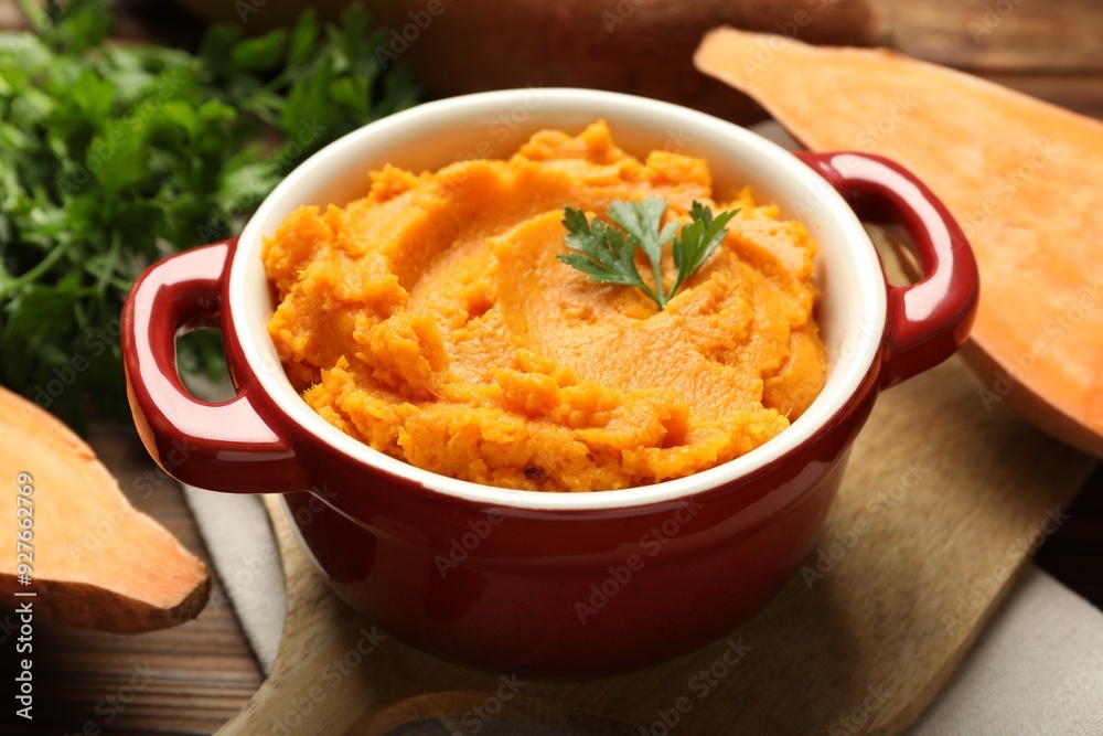 Delicious mashed sweet potatoes in pot, parsley and cut vegetable on wooden table, closeup Delicious mashed sweet potatoes in pot, parsley and cut vegetable on wooden table, closeup
