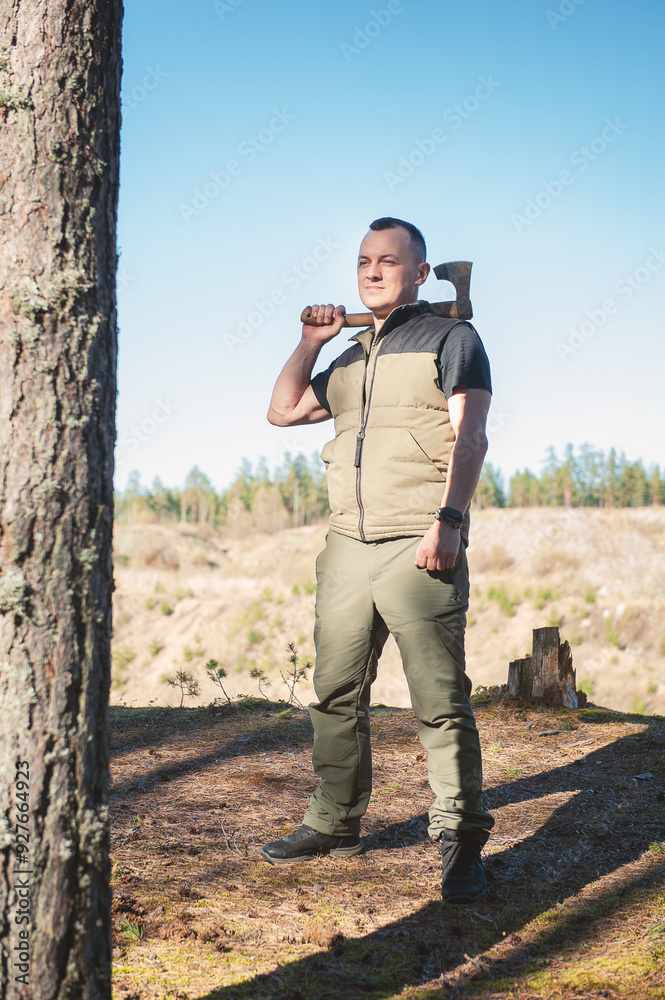 Lumberjack holding axe in forest, standing confidently by a pine tree Lumberjack holding axe in forest, standing confidently by a pine tree