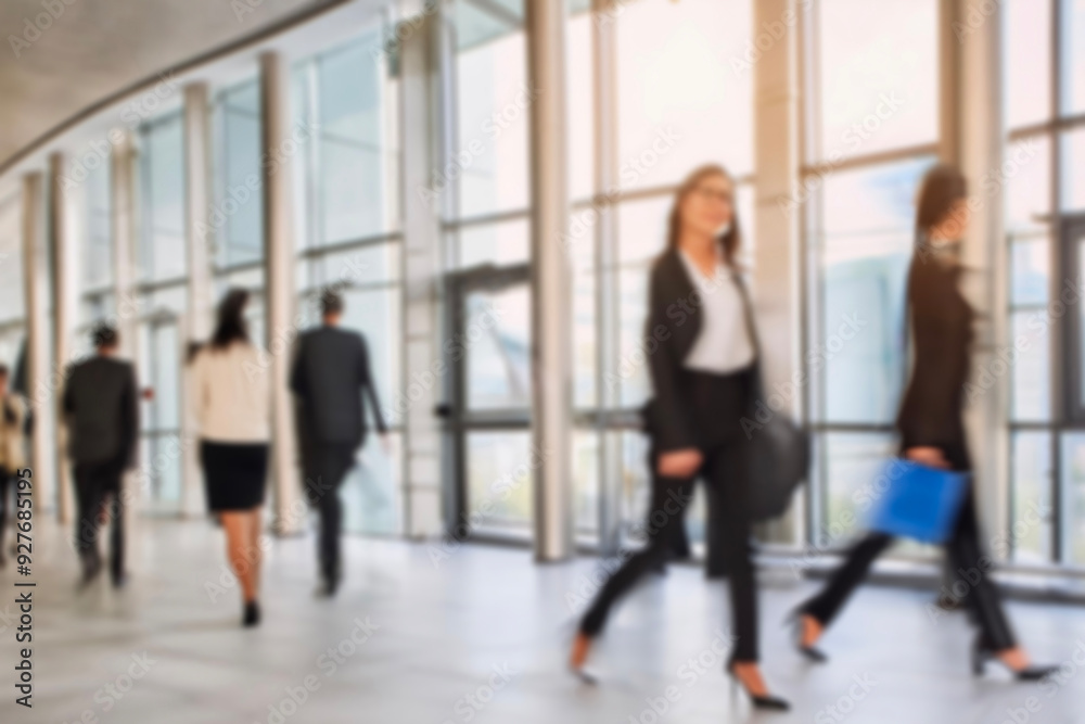 Fototapeta premium business people walking in the corridor of an business center, pronounced motion blur, crowded bright modern light office movement defocused. office background busy. talking and rushing in the lobby.
