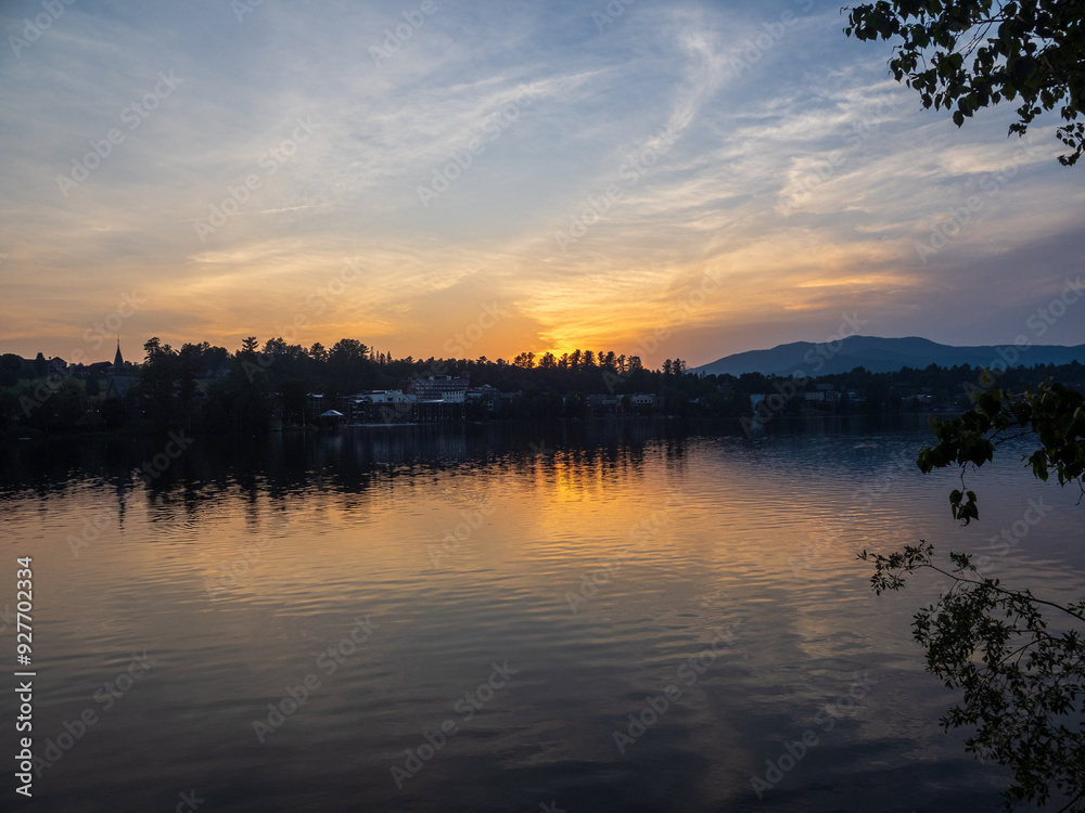 Obraz premium Sunset over Lake Placid with Adirondack Mountains in the background across Mirror Lake in Upstate New York, USA.
