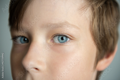 Extreme macro close-up portrait of face. Child boy eyes looking at camera. Blue eyes of teen boy male. Caucasian kid wide opening eyes, smiling. Laser correction