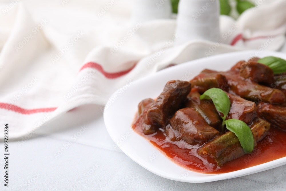 Tasty stew with okra, tomato sauce and basil on white tiled table, closeup. Space for text Tasty stew with okra, tomato sauce and basil on white tiled table, closeup. Space for text