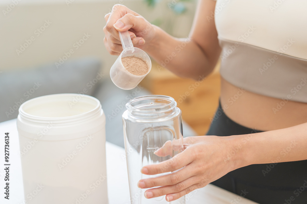 Diet meal replacement for weight loss, asian young woman in sportswear, hand in holding scoop making protein into bottle to shake, drink supplement for muscle after workout at home. Healthy body care. Diet meal replacement for weight loss, asian young woman in sportswear, hand in holding scoop making protein into bottle to shake, drink supplement for muscle after workout at home. Healthy body care.