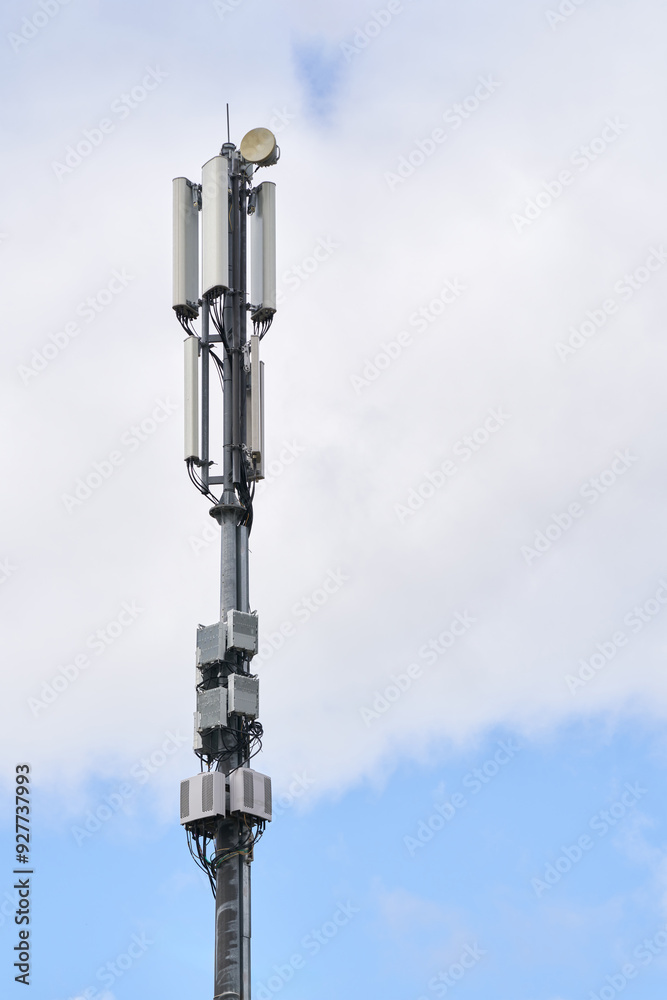 A cell tower with 5G equipment against the sky. A cell tower with 5G equipment against the sky.