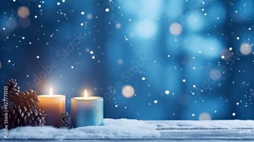 Two burning candles on a snowy wooden surface with a bokeh background.