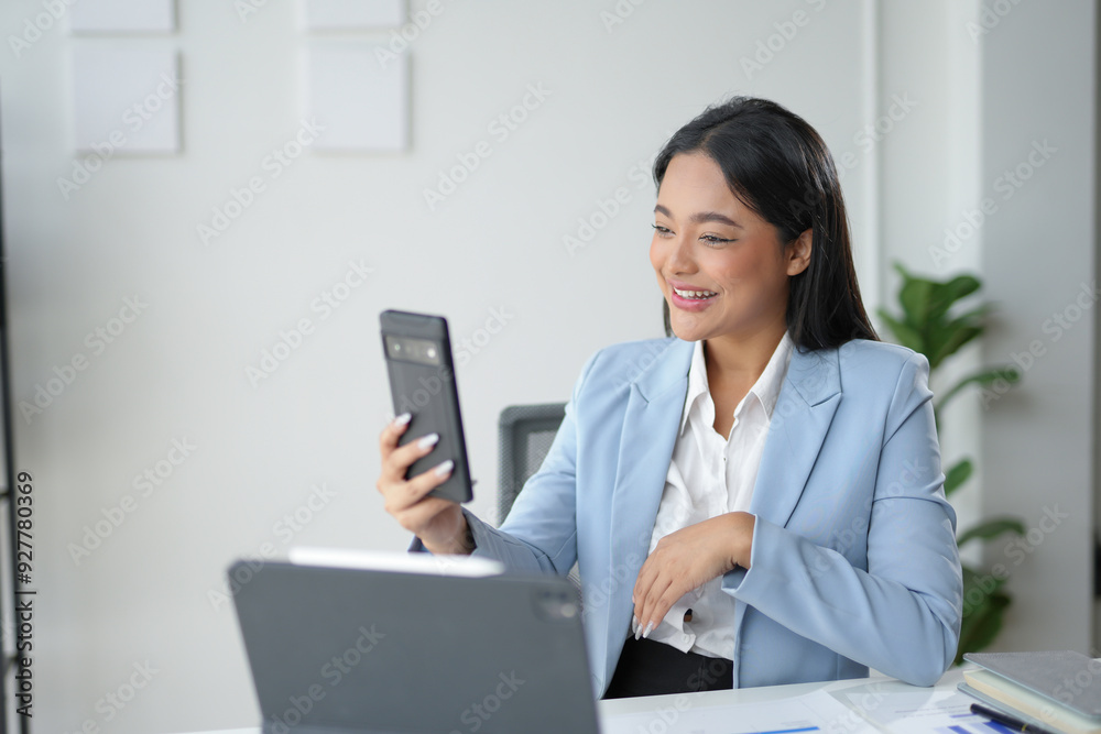 Young asian businesswoman is using a smartphone for a video call while working in a modern office Young asian businesswoman is using a smartphone for a video call while working in a modern office