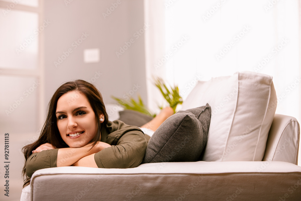 Young woman relaxing on couch at home smiling Young woman relaxing on couch at home smiling
