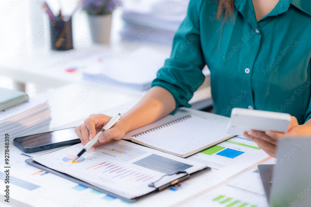 Financial Focus: Professional woman meticulously analyzes charts and crunches numbers with a calculator, embodying the essence of financial planning and accounting. Financial Focus: Professional woman meticulously analyzes charts and crunches numbers with a calculator, embodying the essence of financial planning and accounting.