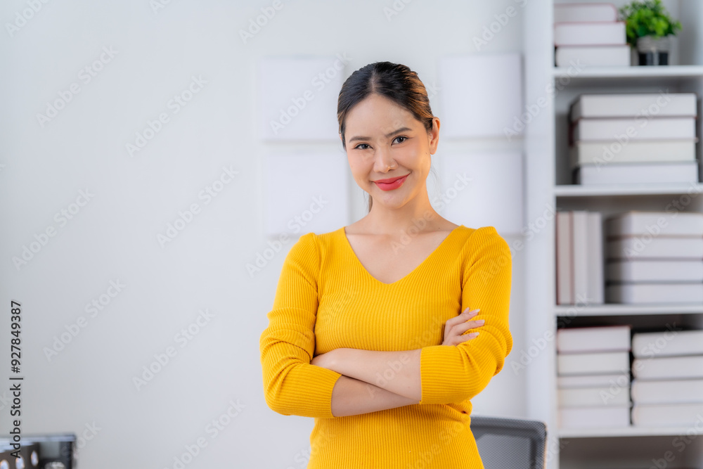 Confident and Ready: A professional woman in a bright yellow sweater stands confidently with arms crossed, exuding a sense of determination and competence in her modern office setting. Confident and Ready: A professional woman in a bright yellow sweater stands confidently with arms crossed, exuding a sense of determination and competence in her modern office setting.