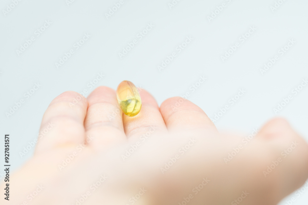 Male hand holding omega 3 soft gel capsule isolated on white background Male hand holding omega 3 soft gel capsule isolated on white background
