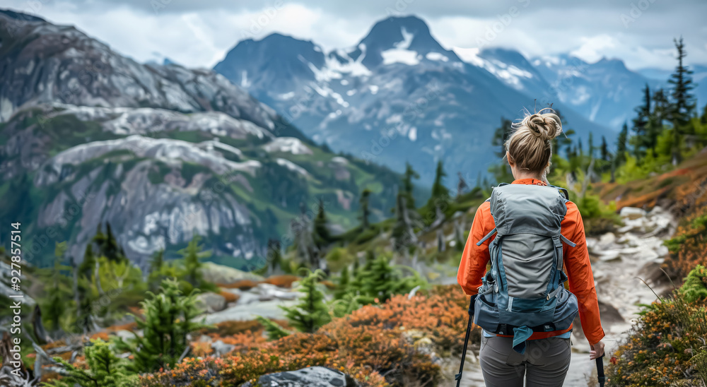 A woman is walking in the mountains with a large backpack on her back. The mountains are covered in snow, and the woman is wearing an orange jacket. Concept of adventure and exploration A woman is walking in the mountains with a large backpack on her back. The mountains are covered in snow, and the woman is wearing an orange jacket. Concept of adventure and exploration