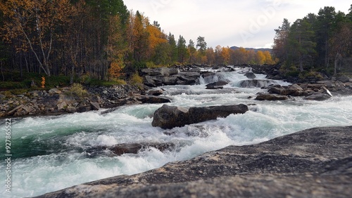 Beautiful whitewater rapids flowing over a rocky river bed in Norway on a crisp autumn day.