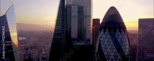 
As the sun begins to set over London, the city's iconic skyline is bathed in a warm, golden glow. From a drone's aerial perspective, the skyscrapers rise majestically, their glass facades reflecting 