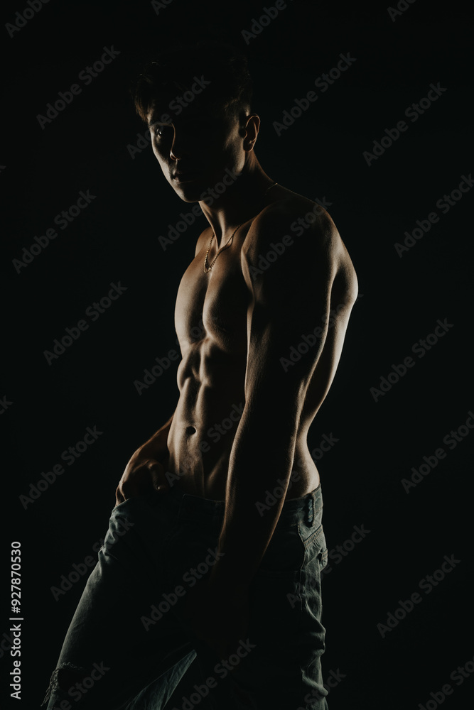 Muscular man posing shirtless in dark, dramatic lighting. Emphasizes fitness, strength, and masculinity. Perfect for concepts related to health, bodybuilding, and physical fitness. Muscular man posing shirtless in dark, dramatic lighting. Emphasizes fitness, strength, and masculinity. Perfect for concepts related to health, bodybuilding, and physical fitness.