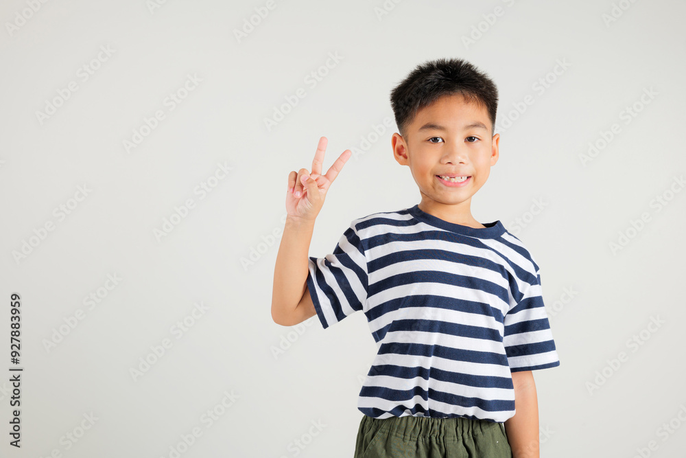 Asian young kid boy showcases optimism and peace by gesturing victory and peace signs in a studio shot with a white background. primary child joyful smile speaks of success, V sign finger Asian young kid boy showcases optimism and peace by gesturing victory and peace signs in a studio shot with a white background. primary child joyful smile speaks of success, V sign finger
