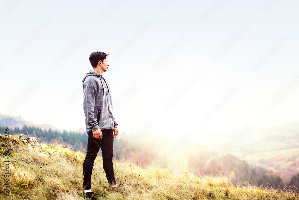 Male runner resting after jog in nature on dirt running trail, enjoying view. Morning running training for young man. Male runner resting after jog in nature on dirt running trail, enjoying view. Morning running training for young man.