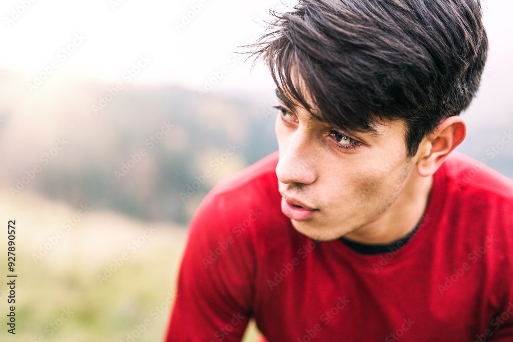 Male runner resting after jog in nature on dirt running trail, enjoying view. Morning running training for young man. Male runner resting after jog in nature on dirt running trail, enjoying view. Morning running training for young man.