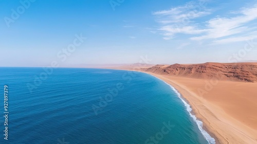 Aerial view of a pristine beach and coastline, with clear blue water and dramatic red cliffs.