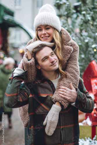 Photography Beautiful young loving couple embracing, kissing, enjoying winter vacation, cold snowy day on a street city Christmas market outdoors