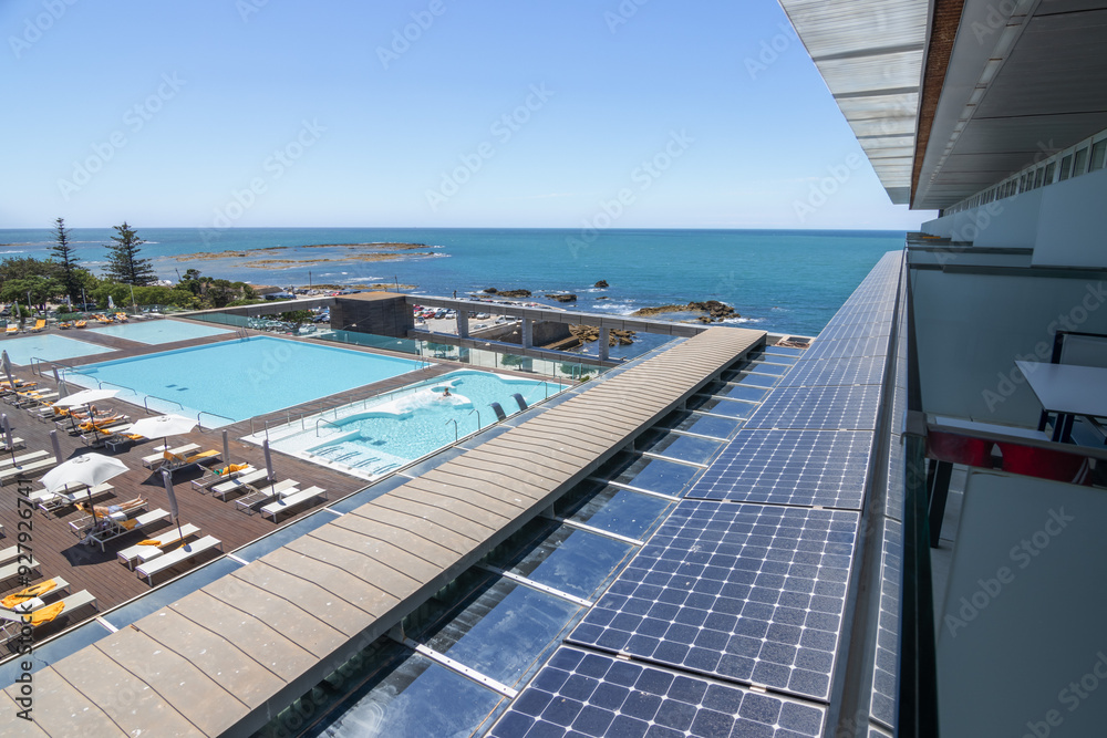 Fototapeta premium Views of the sea, the pool, people on the sun loungers, solar panels on the façade of the building. Hotel, vacation, tourism, clean energy, travel.