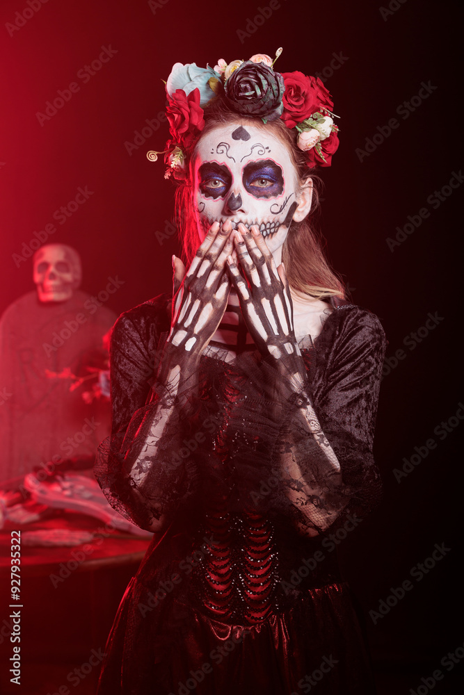Fototapeta premium Dark lady blowing kisses during Dia de los Muertos, preserving cultural traditions between generations. Woman doing affectionate gesture, wearing la Catrina costume to celebrate Mexican culture