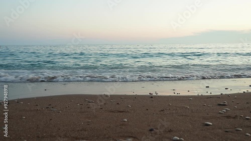 Waves gently lap at shore during stunning sunset over ocean. Golden sunlight reflects off waves as they roll onto shore, creating tranquil atmosphere at sunset by sea. Montenegro summer Canj photo