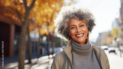 Portrait of beautiful happy smiling African mature woman with curly hair standing in autumn city