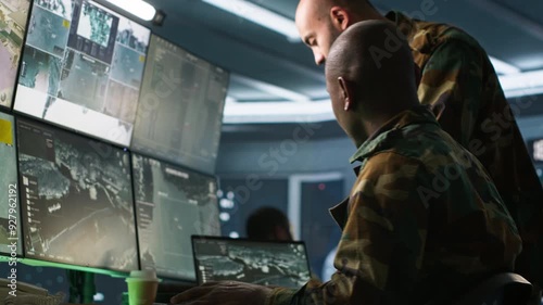 Army colleagues looking at screens in command center housing operational missile defense system designed to intercept ballistic rockets. Experts using tracking gear and radar systems, camera A