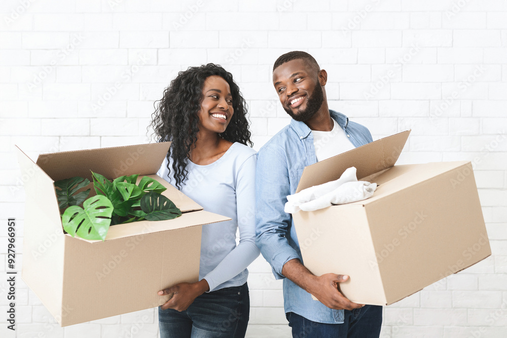 Young happy african couple holding cardboard boxes, smiling and looking at each other Young happy african couple holding cardboard boxes, smiling and looking at each other