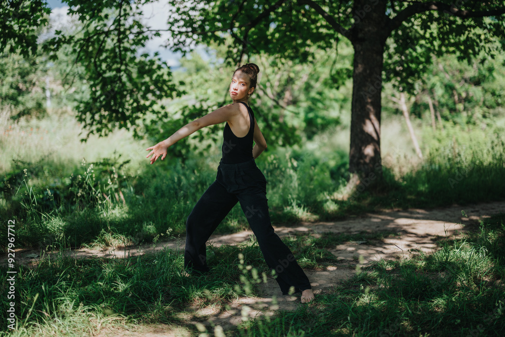 Young woman gracefully performing modern dance in a serene forest setting on a sunny day. Young woman gracefully performing modern dance in a serene forest setting on a sunny day.