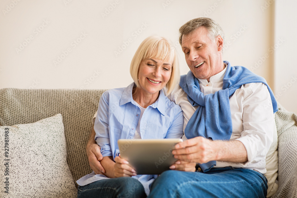 Surfing internet. Mature couple using digital tablet, resting on sofa at home Surfing internet. Mature couple using digital tablet, resting on sofa at home