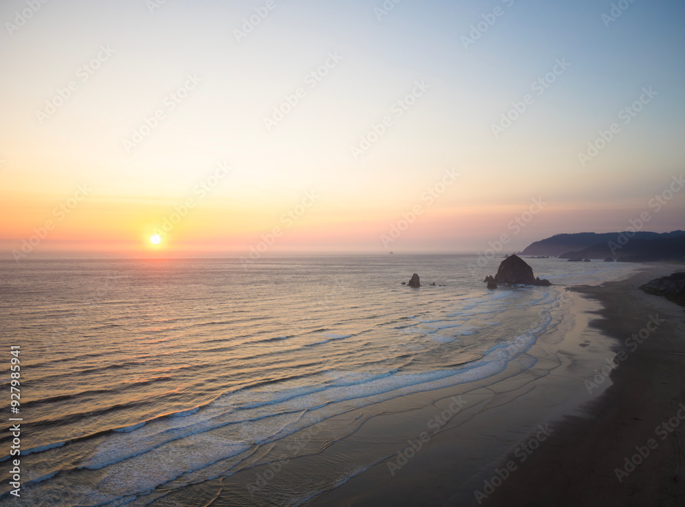 The ocean is calm and the sun is setting, creating a beautiful The ocean is calm and the sun is setting, creating a beautiful