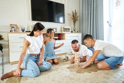 Family playing a jenga game on the floor in a bright living room during the afternoon