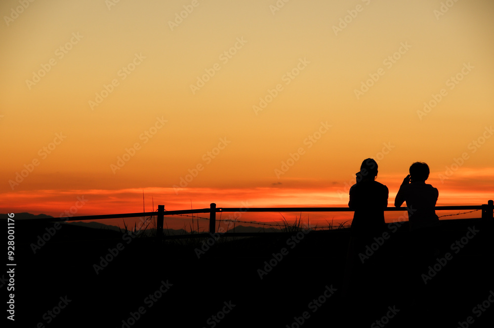 Fototapeta premium 夕焼けに溶け込む二人