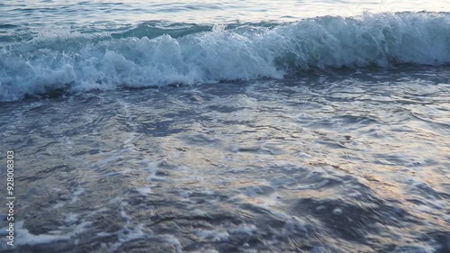 Waves gently lap at shore during stunning sunset over ocean. Golden sunlight reflects off waves as they roll onto shore, creating tranquil atmosphere at sunset by sea. Montenegro summer Canj photo