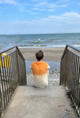 Man in t shirt and pants standing on dock and looking on sea horizon