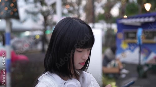 Wallpaper Mural In Shilin District, Taipei City, Taiwanese woman in her twenties on date, standing and using smartphone during evening at amusement park in Taiwan. Torontodigital.ca