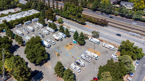 Aerial drone view of RV parking area serving as a safe parking space for homeless. The lot features designated spaces for disabled parking and is surrounded by trees and greenery