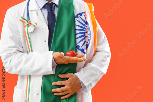 Male physician with flag of India, ribbon and heart on orange background, closeup. National Doctor's Day celebration photo