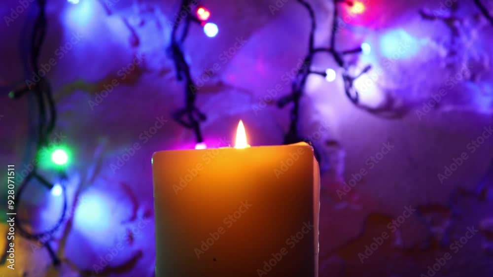 Primer plano de una vela blanca con llama rodeada de varias luces con bombillos de varios colores en movimiento en la oscuridad