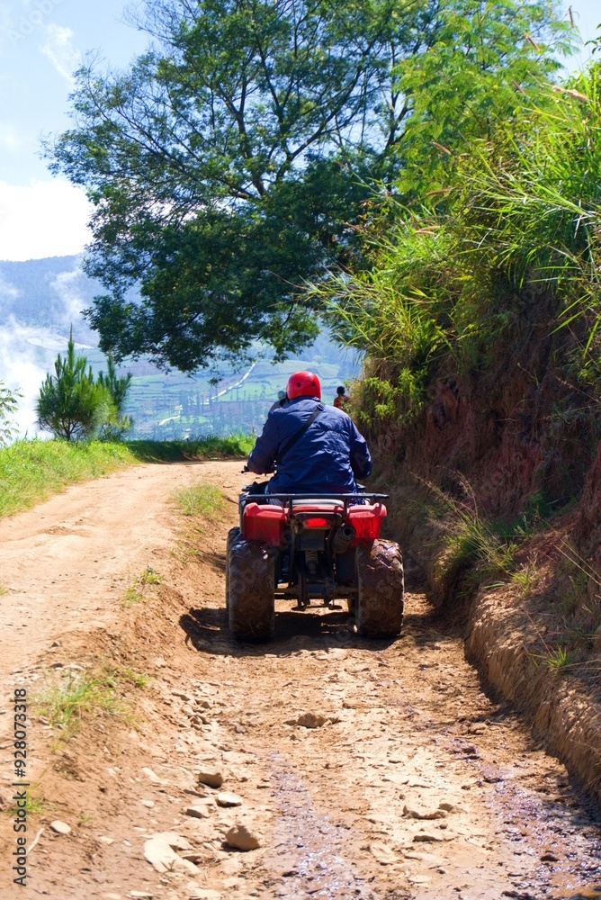 Fototapeta premium A red ATV is parked on a dirt road with a view of the mountains.