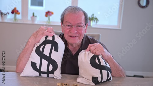 wealthy senior citizen laughing holding two money bags after winning an inheritance photo