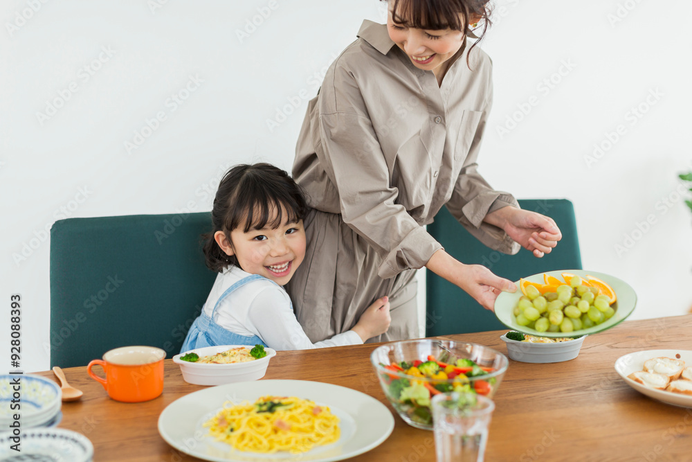食事の準備をする母親に抱きつく女の子 食事の準備をする母親に抱きつく女の子