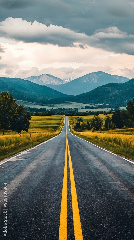 Naklejka premium A bright, beautiful road with green fields and distant mountains, perfect for adventure and freedom.